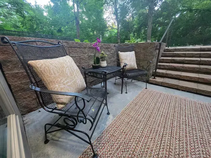 A patio with two chairs , a table and a rug.