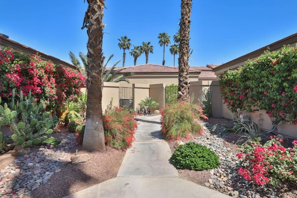 A walkway leading to a house with palm trees and flowers.- California- Trip- Summer