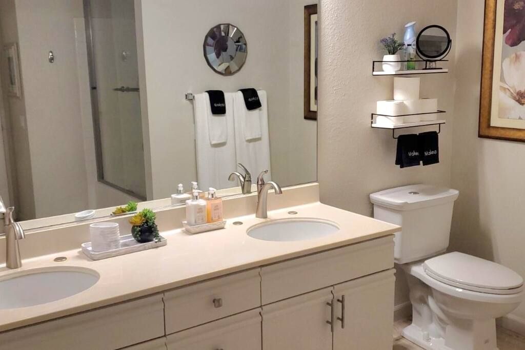 A bathroom with two sinks , a toilet and a mirror.- California- Trip- Summer