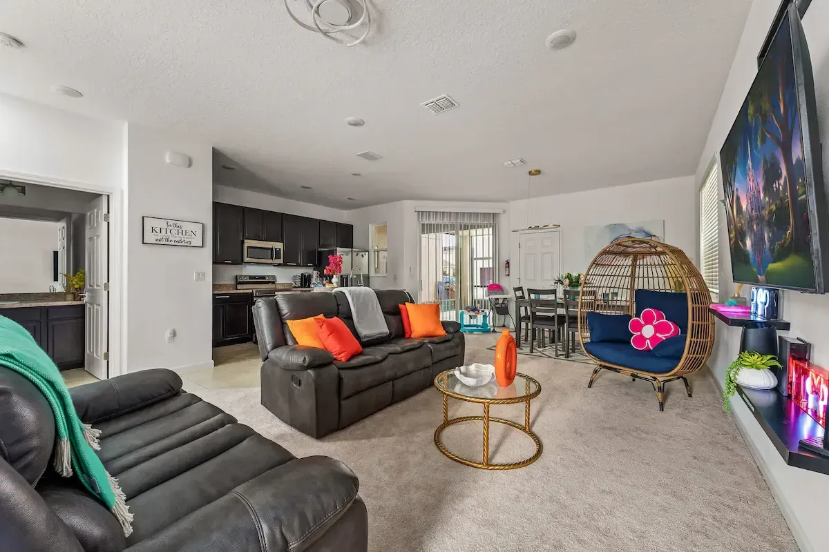 A living room filled with furniture and a flat screen tv. Spacious opening with Disney inspired pillows.