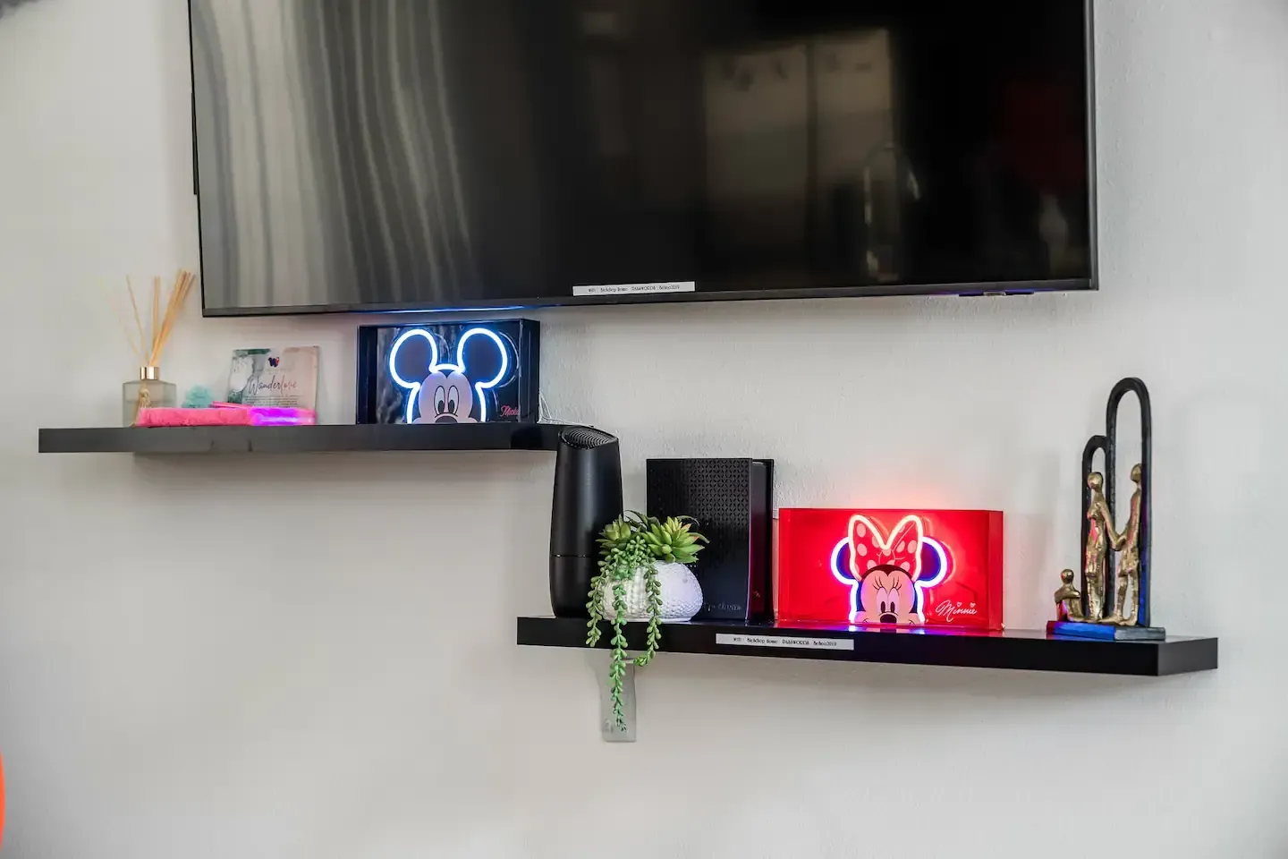 A living room with two shelves and a flat screen tv. Mickey mouse inspired decor.