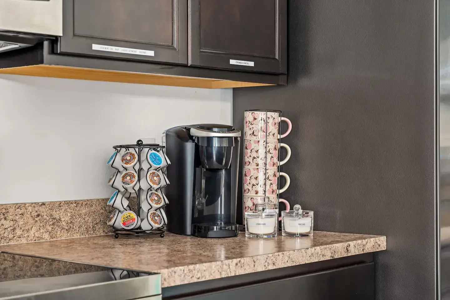 A kitchen counter with a coffee maker and cups on it.
