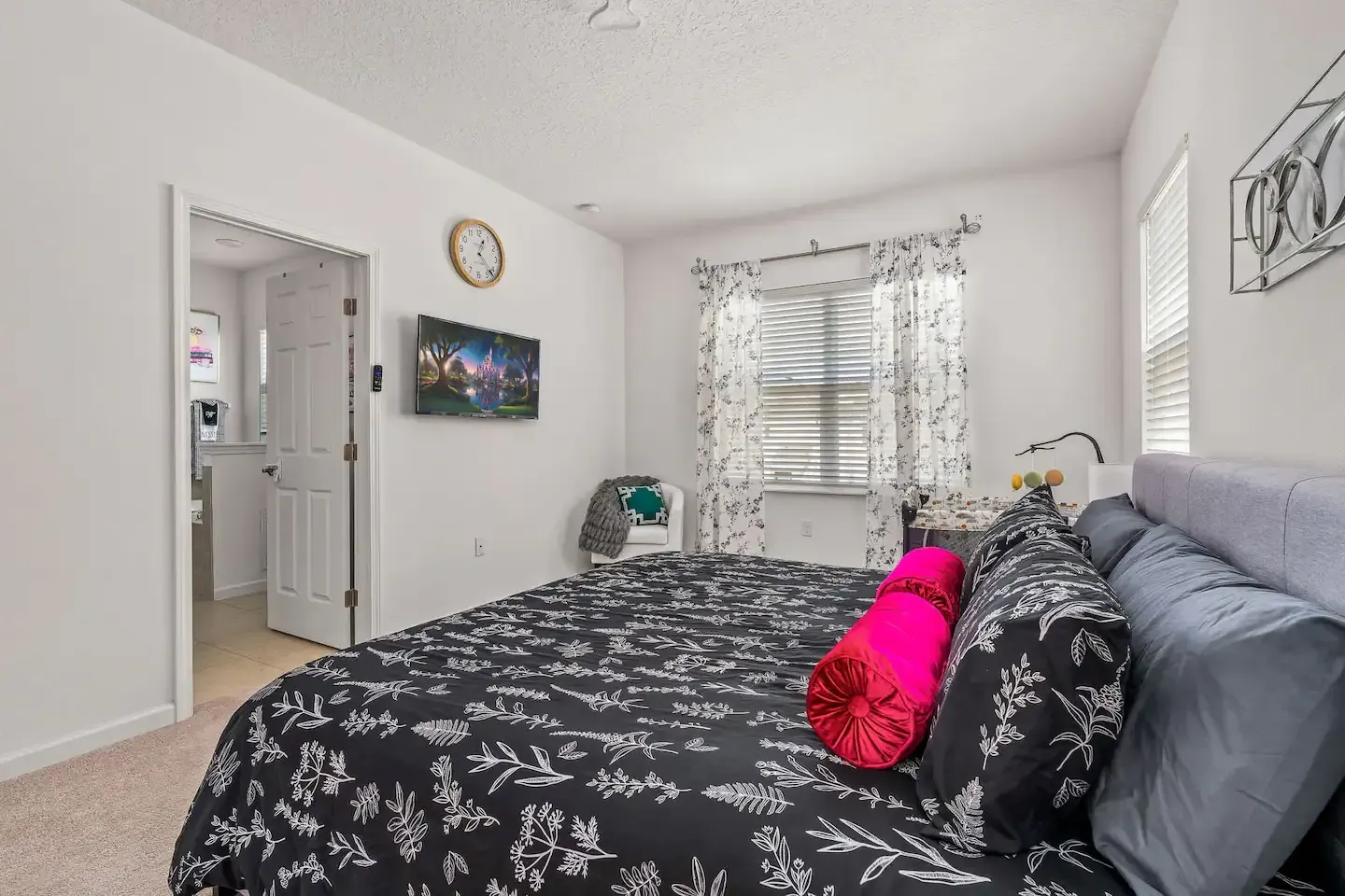 A bedroom with a large bed and a flat screen tv on the wall.
