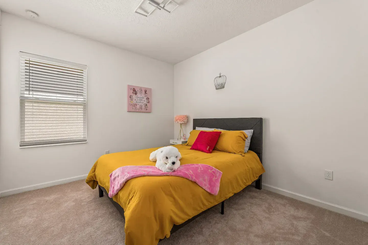 A bedroom with a bed , two windows , a lamp and a teddy bear on the bed.