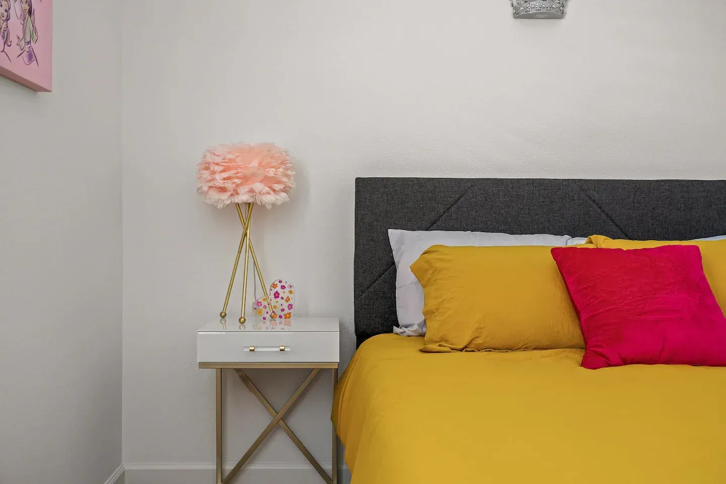 A bedroom with a bed , nightstand , lamp and yellow sheets.