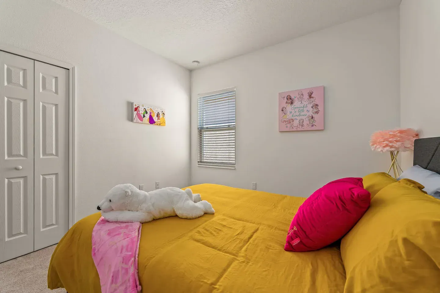 There is a teddy bear laying on the bed in the bedroom.
