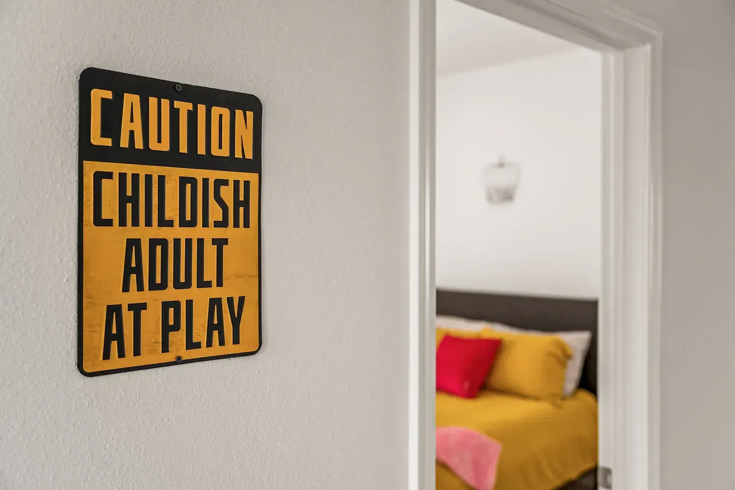 A sign on a wall that says caution childish adult at play. A room for two love birds to unwind.