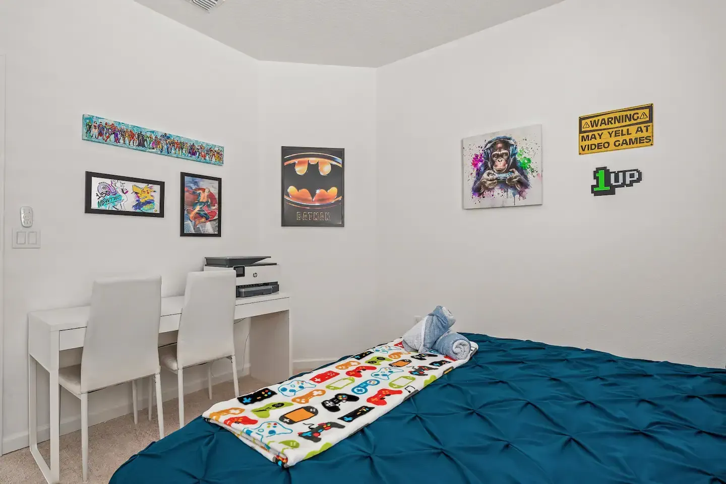 A bedroom with a bed, desk, chairs, and paintings on the wall. It is great for children to relax and unwind.