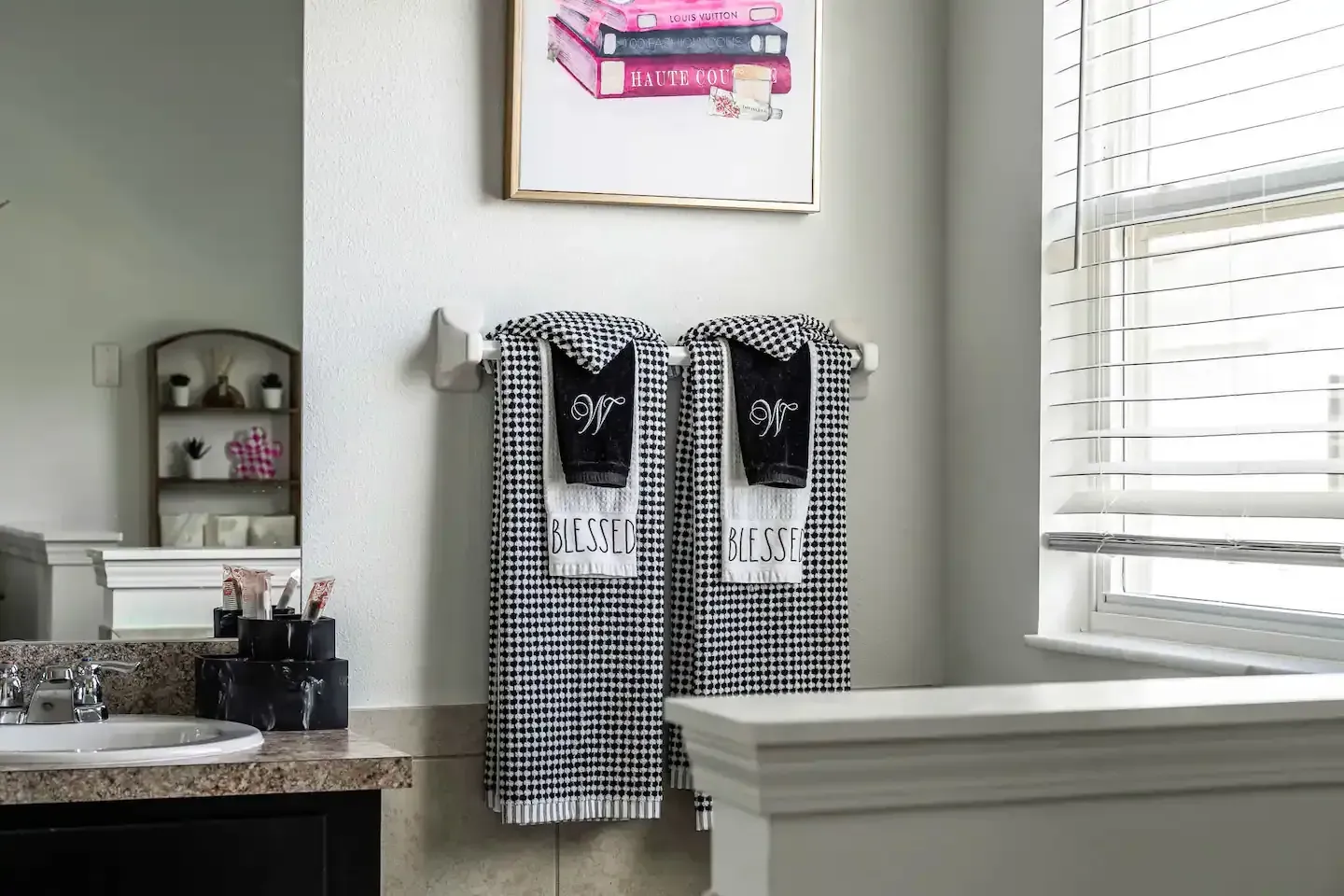 A bathroom with two towels hanging on a towel rack and a sink.