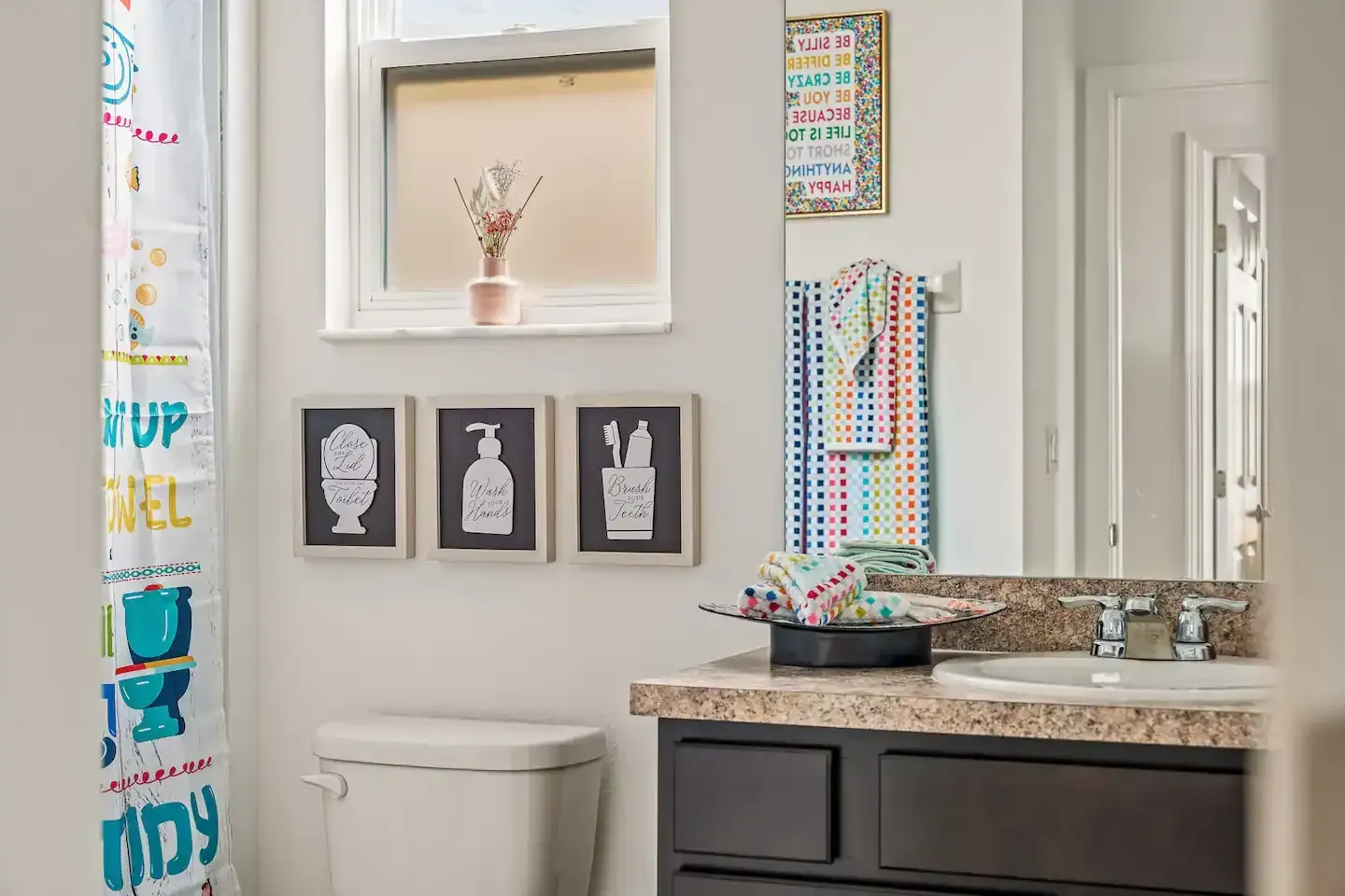A bathroom with a toilet , sink , mirror and shower curtain.