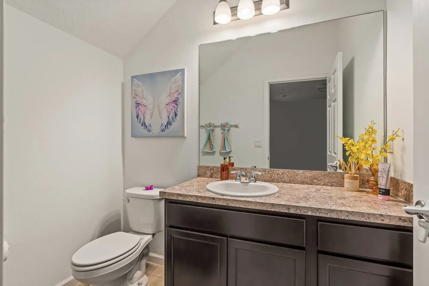 A bathroom with a toilet , sink , and mirror.