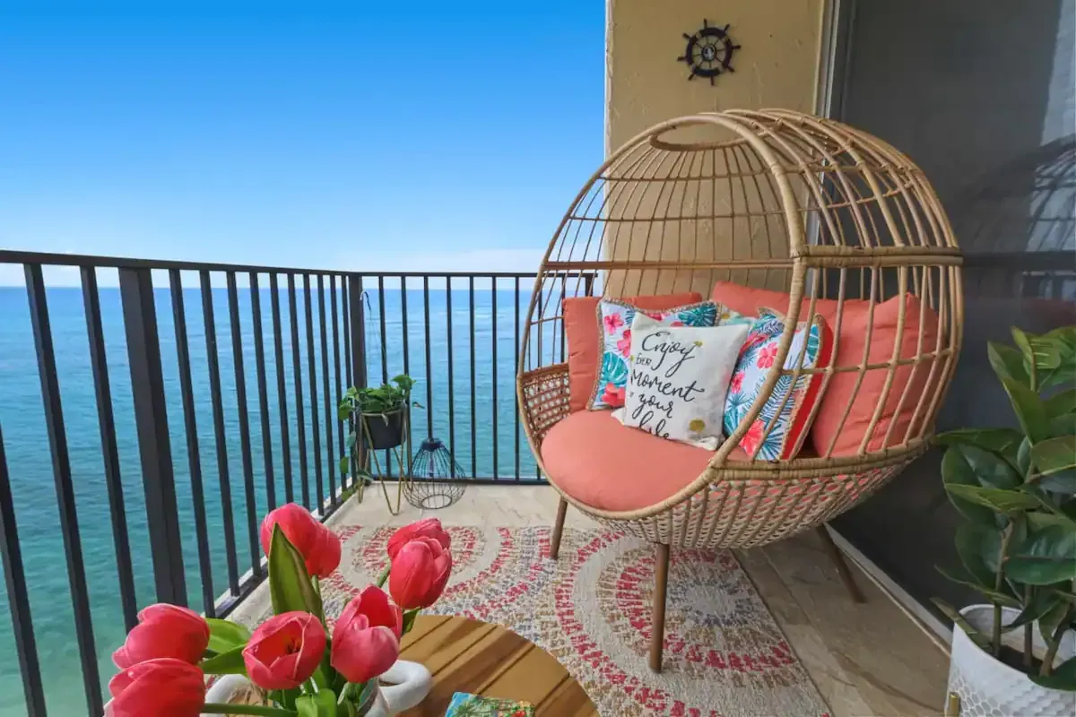 A balcony with a chair and a table overlooking the ocean.