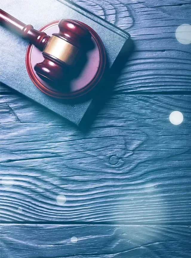 Martillo sobre un libro de leyes cerrado, sobre un fondo de veta de madera azul.