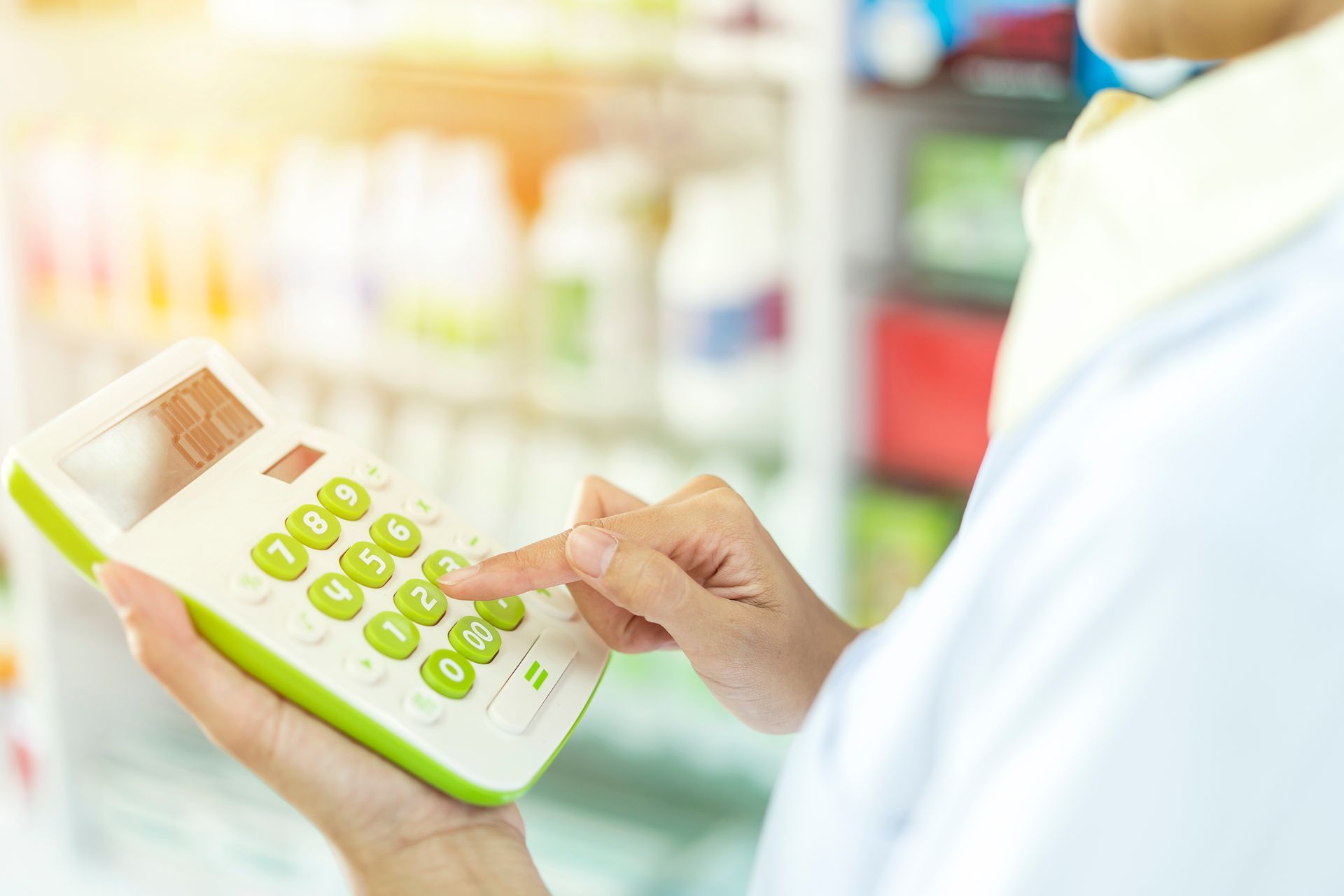 Buchhaltung Apotheke: Eine Person benutzt in einer Apotheke einen Taschenrechner.