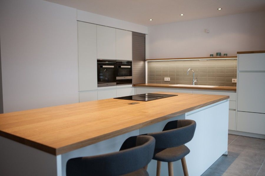 Holzwaschtisch mit schwarzer Oberseite und weißer Front mit zwei Schubladen, die dieselbe Breite wie der Schrank haben. Ein weißes rundes modernes Waschbecken mit verchromter Mischbatterie steht oben rechts auf dem Schrank.