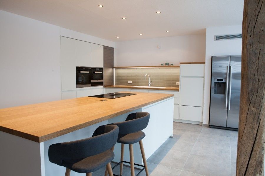 Holzwaschtisch mit schwarzer Oberseite und weißer Front mit zwei Schubladen, die dieselbe Breite wie der Schrank haben. Ein weißes rundes modernes Waschbecken mit verchromter Mischbatterie steht oben rechts auf dem Schrank.