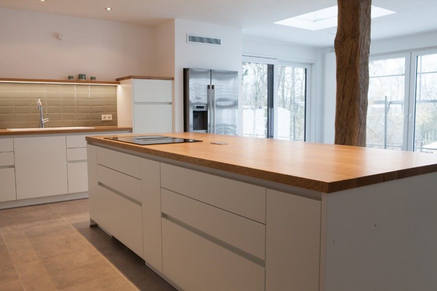 Holzwaschtisch mit schwarzer Oberseite und weißer Front mit zwei Schubladen, die dieselbe Breite wie der Schrank haben. Ein weißes rundes modernes Waschbecken mit verchromter Mischbatterie steht oben rechts auf dem Schrank.