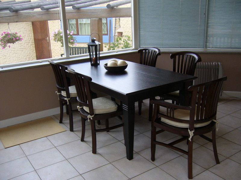 Holzwaschtisch mit schwarzer Oberseite und weißer Front mit zwei Schubladen, die dieselbe Breite wie der Schrank haben. Ein weißes rundes modernes Waschbecken mit verchromter Mischbatterie steht oben rechts auf dem Schrank.