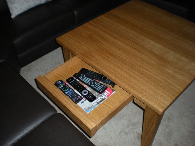 Holzwaschtisch mit schwarzer Oberseite und weißer Front mit zwei Schubladen, die dieselbe Breite wie der Schrank haben. Ein weißes rundes modernes Waschbecken mit verchromter Mischbatterie steht oben rechts auf dem Schrank.