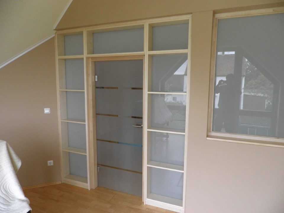 Holzregale um eine Milchglastür direkt in die Wand gebaut mit Milchglas als Rückwand und passendem Fenster im Innenraum aus hellem Holzrahmen und Milchglaseinsatz