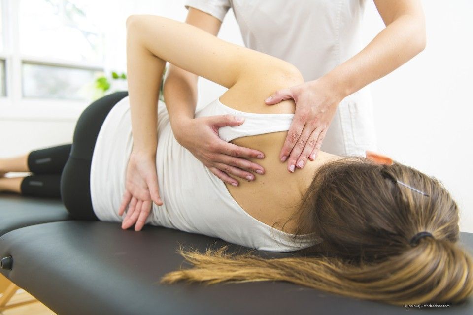Frau wird auf einer Liege am Rücken und Schultern behandelt und massiert