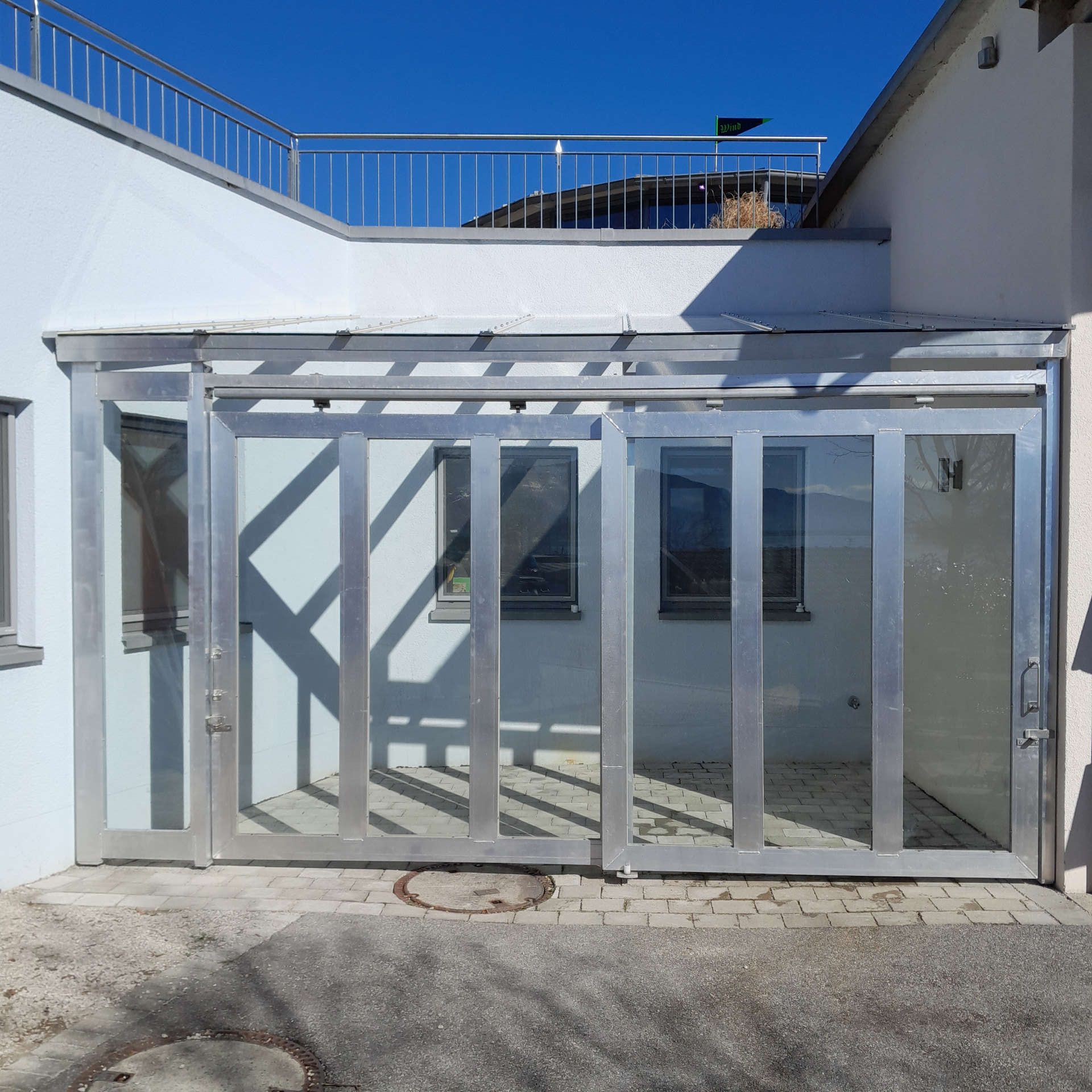Vordachkonstruktion mit zwei Frontschiebetüren aus Aluminium mit Festverglasung und geschlossenen Türen von außen