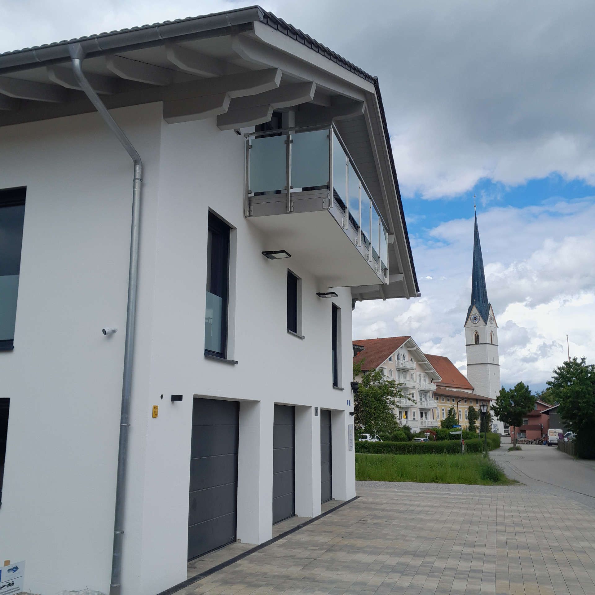 Ein weißes Haus mit einem Balkon direkt unter dem Dach (Seitenansicht)