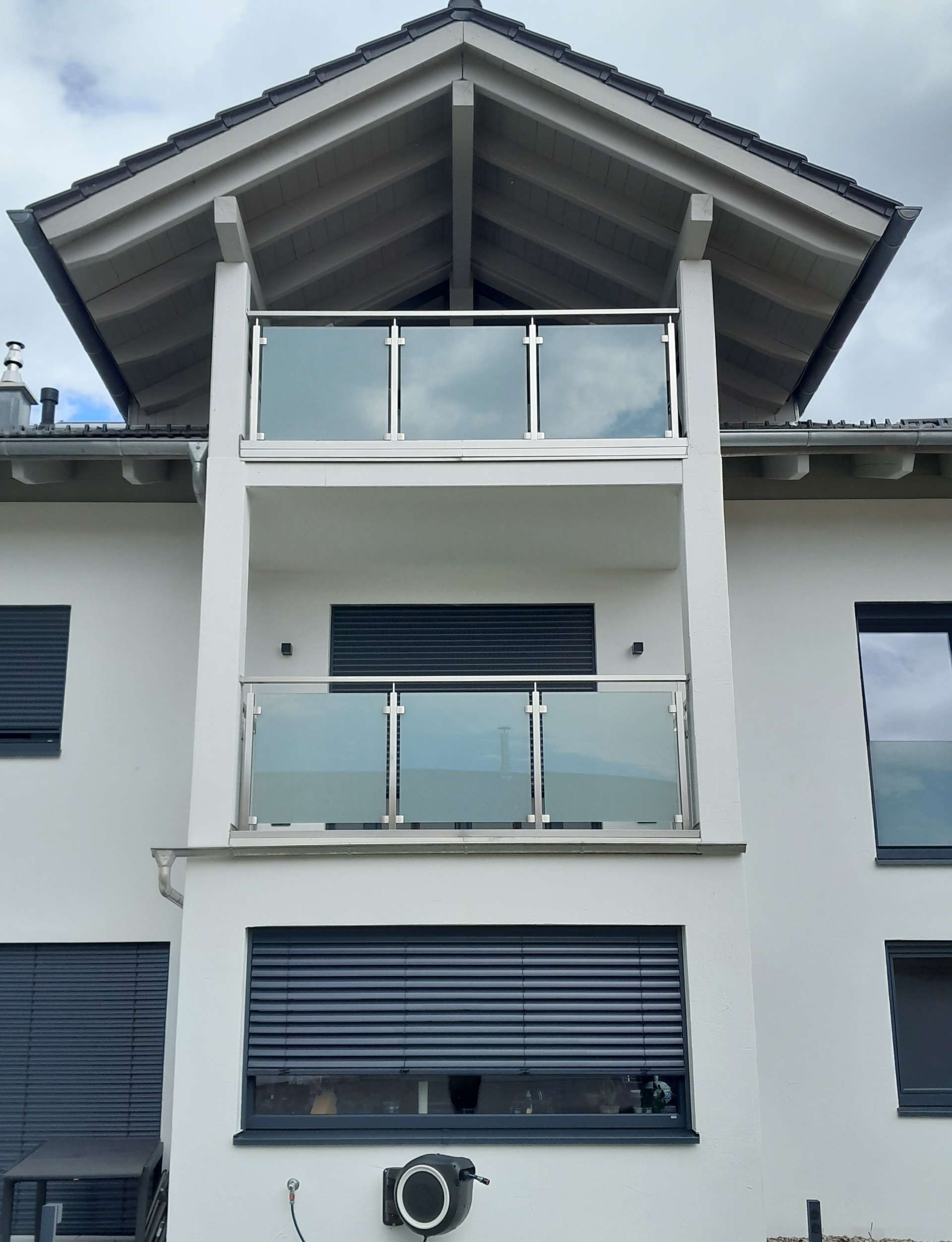 Ein weißes Haus mit 2 Balkonen übereinander (Frontansicht)