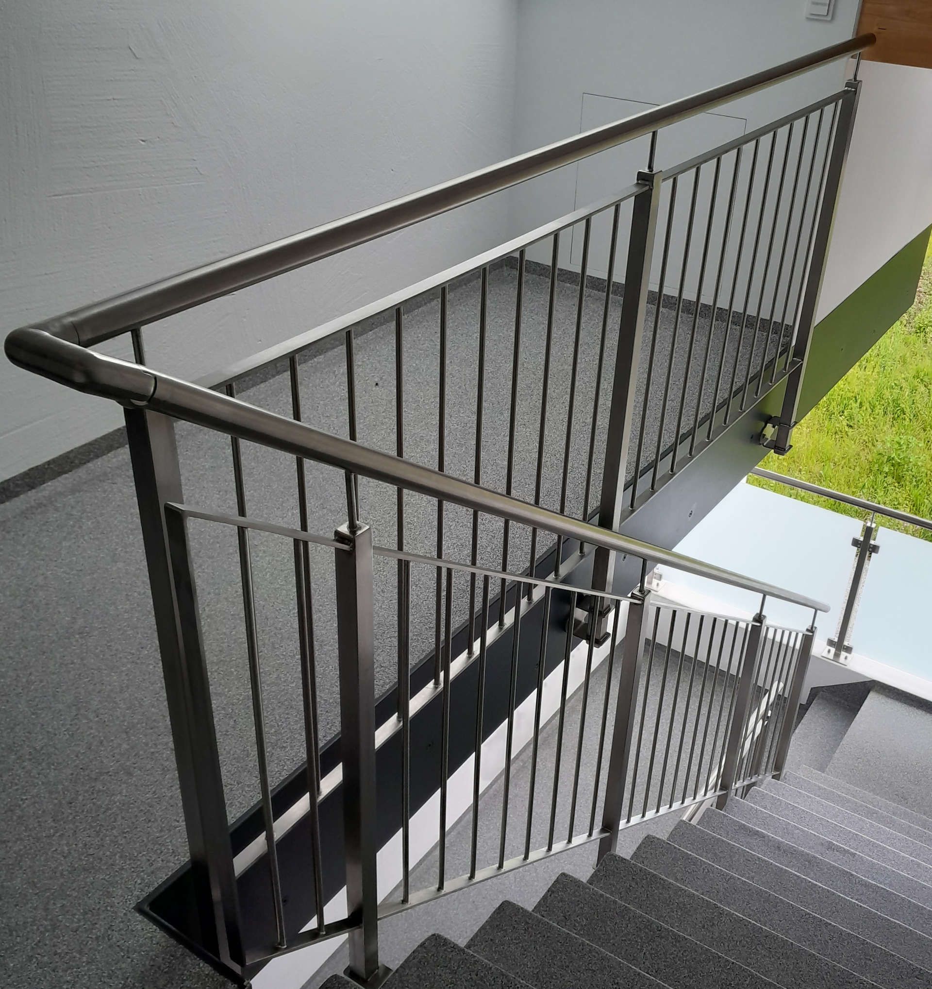 Eine Treppe mit einem Metallgeländer und einem Glasgeländer