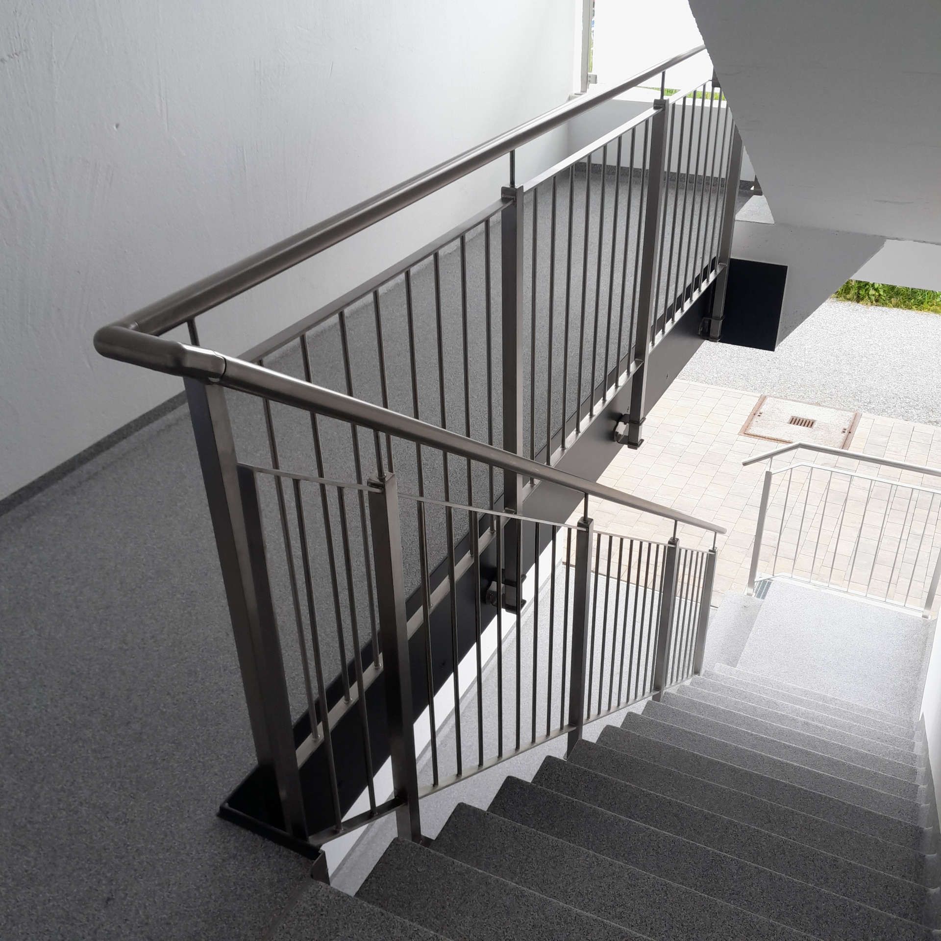 Eine Treppe mit einem Metallgeländer und einer Spiegelung des Geländers in der Treppe