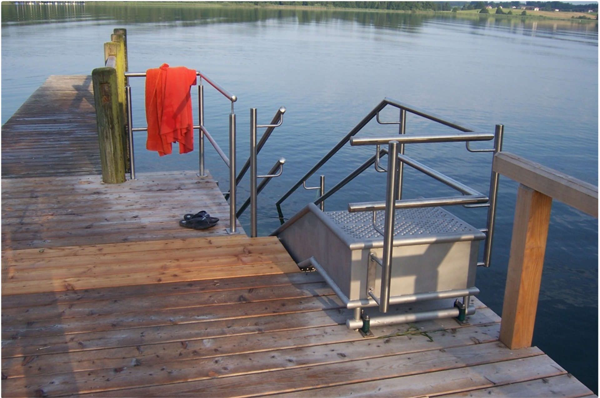 Badetreppe aus Metall mit Geländer an einem Holzsteg am See