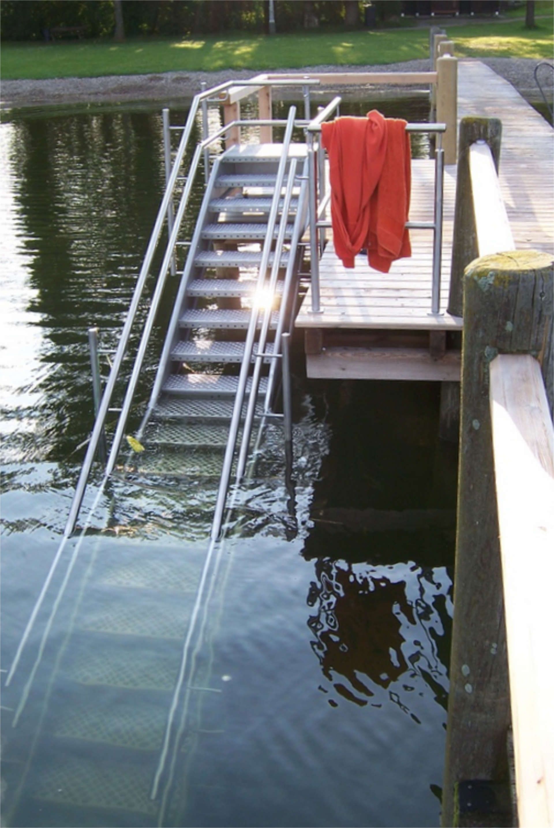 Badetreppe aus Metall mit Geländer an einem Holzsteg am See