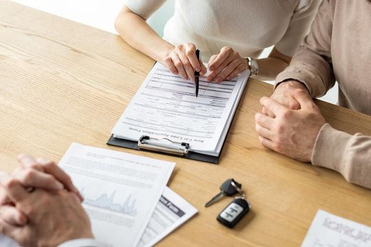 Un hombre y una mujer están sentados en una mesa firmando un documento.