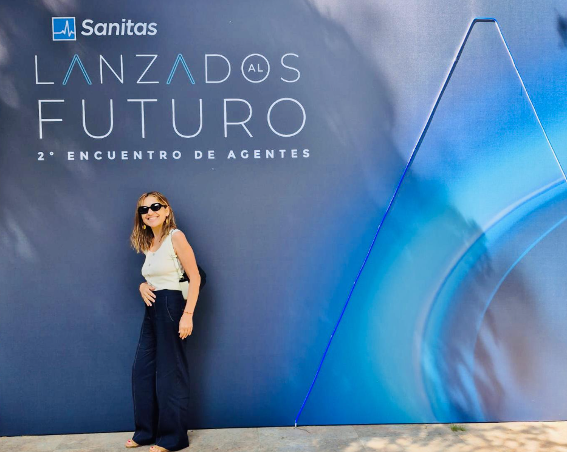 Una mujer está parada frente a un cartel que dice sanitas