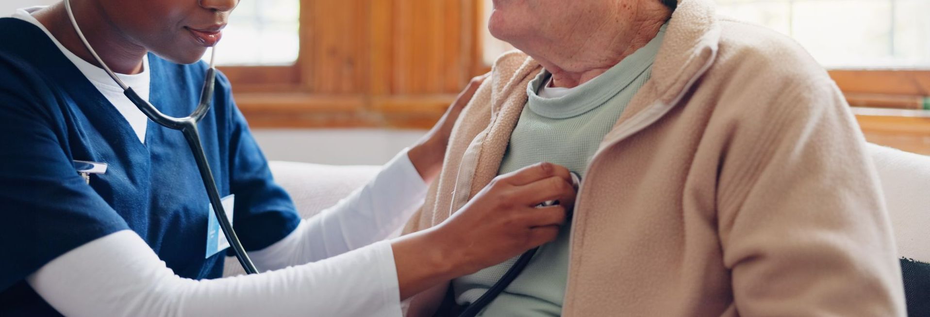 Une femme qui tient un stéthoscope sur la poitrine d'une personne agée