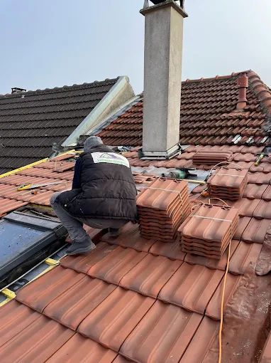 Un couvreur à côté de piles de tuiles.