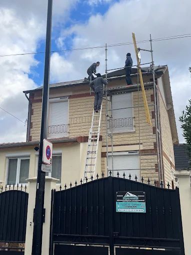 Trois couvreurs et un portail noir.sur le toit d'une maison.