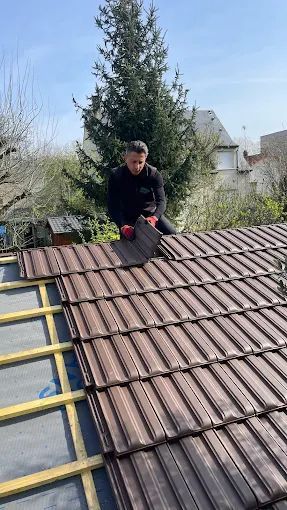 Stéphane Godiche pose une tuile sur un toit.