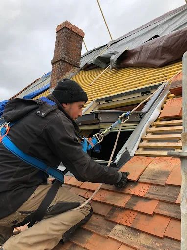 Un couvreur à côté d'une fenêtre de toit.