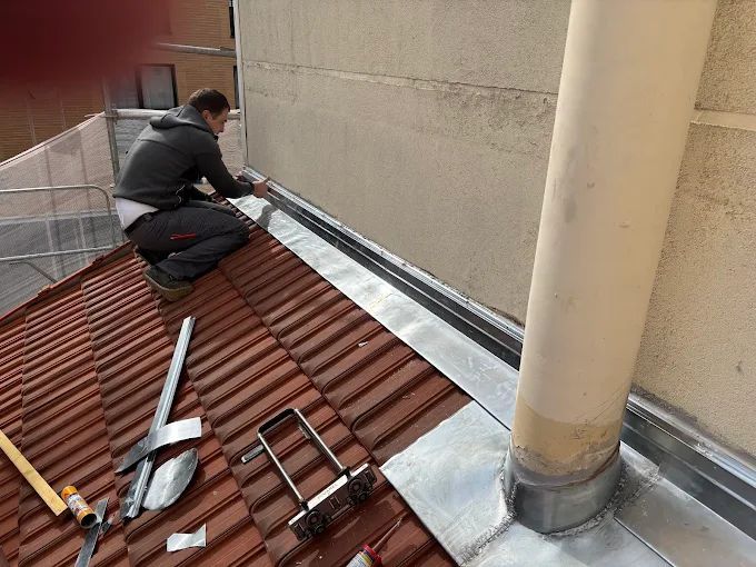 Un couvreur pose du zinc sur un toit.