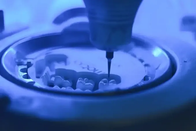 Molde dental con herramientas y tapas de dientes sobre una superficie blanca.