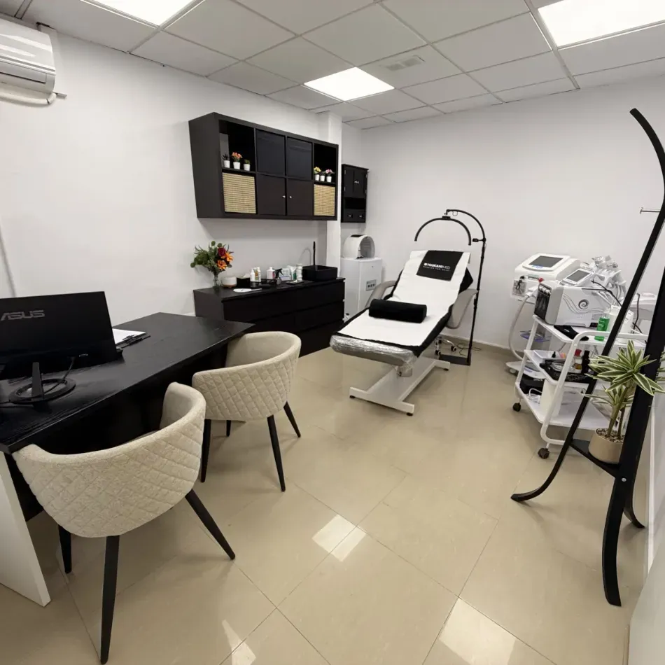 Consultorio médico moderno con escritorio, sillas, camilla y equipo de diagnóstico.