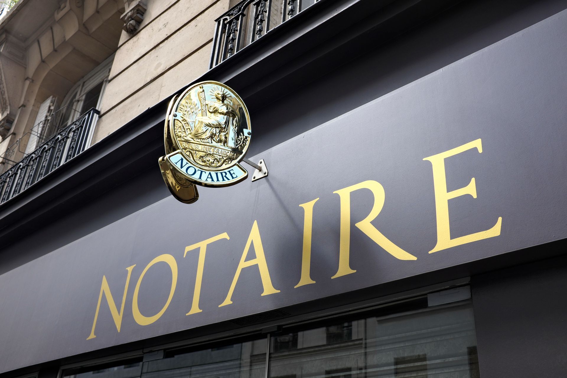 Enseigne d'un cabinet notarial avec lettres dorées et emblème circulaire.