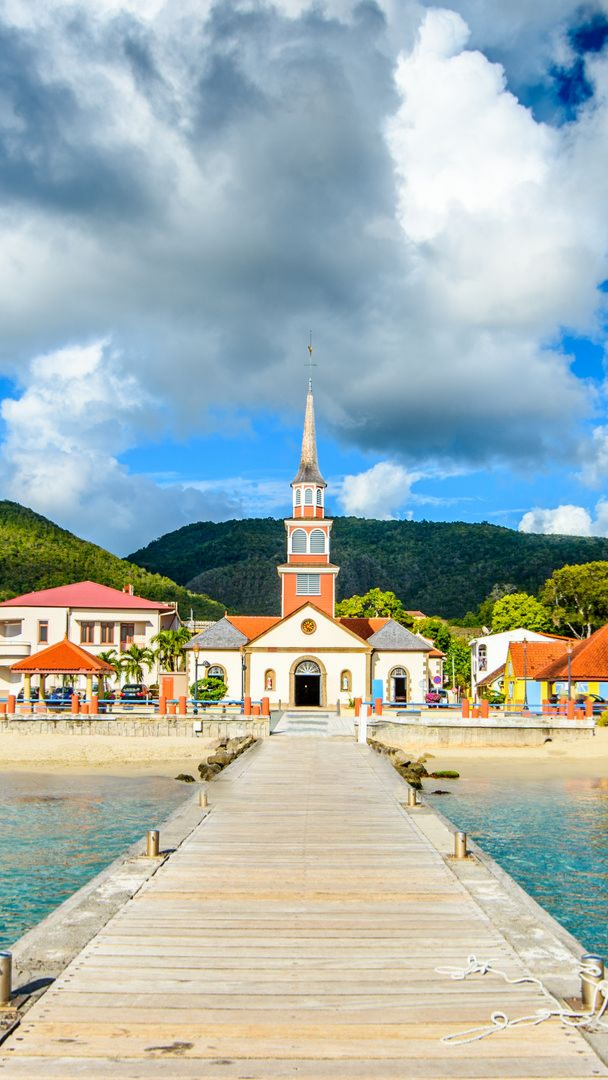 Un bâtiment au bout d'une jetée en bois, mer bleue.