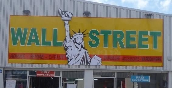 Enseigne d'un magasin représentant la statue de la Liberté, fond jaune, texte vert.