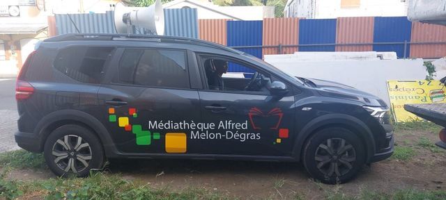 Voiture noire portant le logo Médiathèque Alfred–Melon-Dégras.