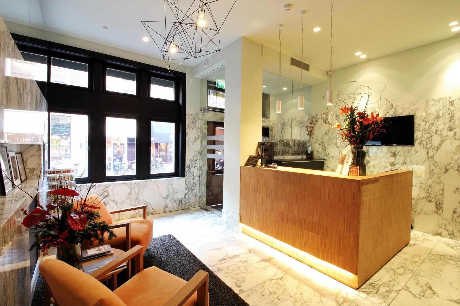 A reception area with a wooden counter and chairs of The Bank Hotel