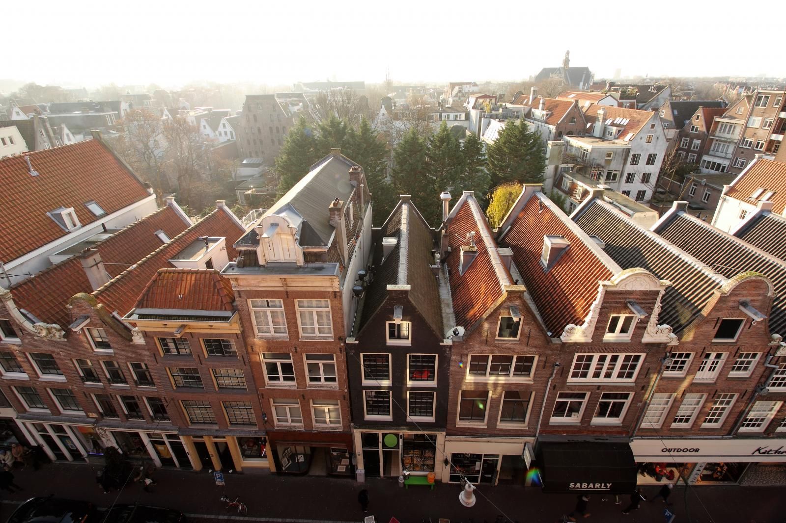 An aerial view of Amsterdam with a lot of buildings and roofs of The Bank Hotel