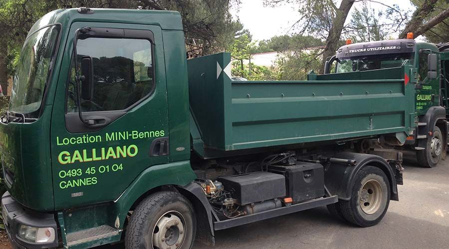 Camions-bennes verts, logo « Galliano », stationnés sur la route. Inscription « Location MINI » et numéro de téléphone visibles.