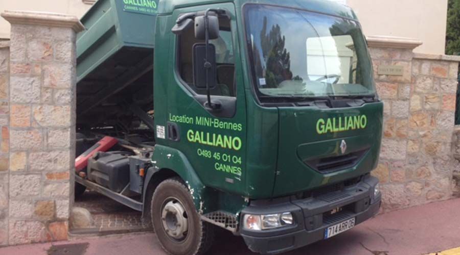 Camion Galliano vert coincé dans une ouverture dans un mur de pierre, Cannes, France. La benne est relevée.